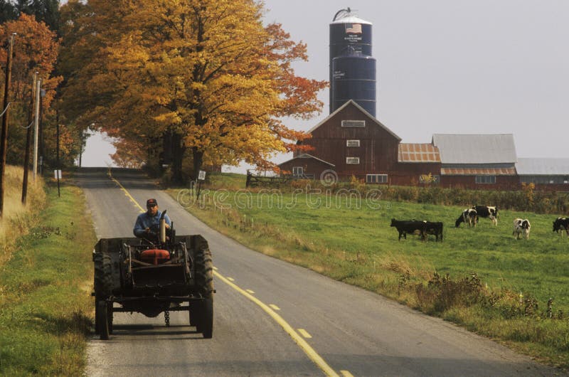Tractor en el camino de campo con el granero y el silo en fondo en el otoño, VT fotos de archivo libres de regalías Tractor en el camino de campo con el granero y el silo en fondo en el otoño, VT fotos de archivo libres de regalías