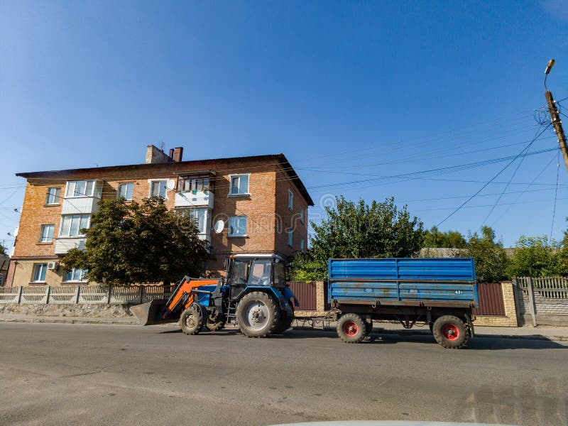 A tractor pulling a trailer down a street next to a building royalty free stock photos