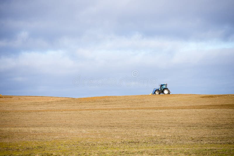 Tractor wide open crop field in rural farm area