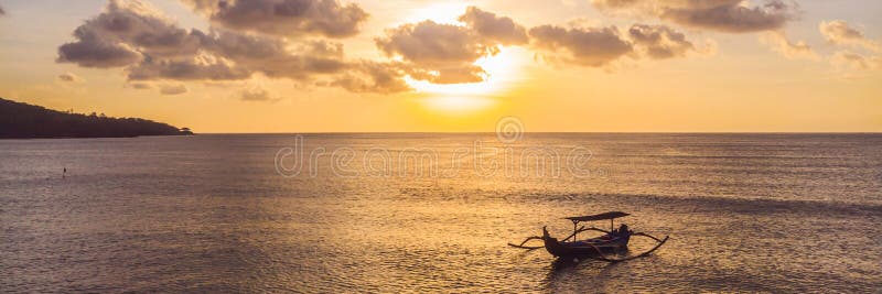 Traditional Balinese boat Jukung at Jimbaran beach at sunset in Bali, Indonesia Photo from the drone BANNER, long format royalty free stock photography Traditional Balinese boat Jukung at Jimbaran beach at sunset in Bali, Indonesia Photo from the drone BANNER, long format royalty free stock photography