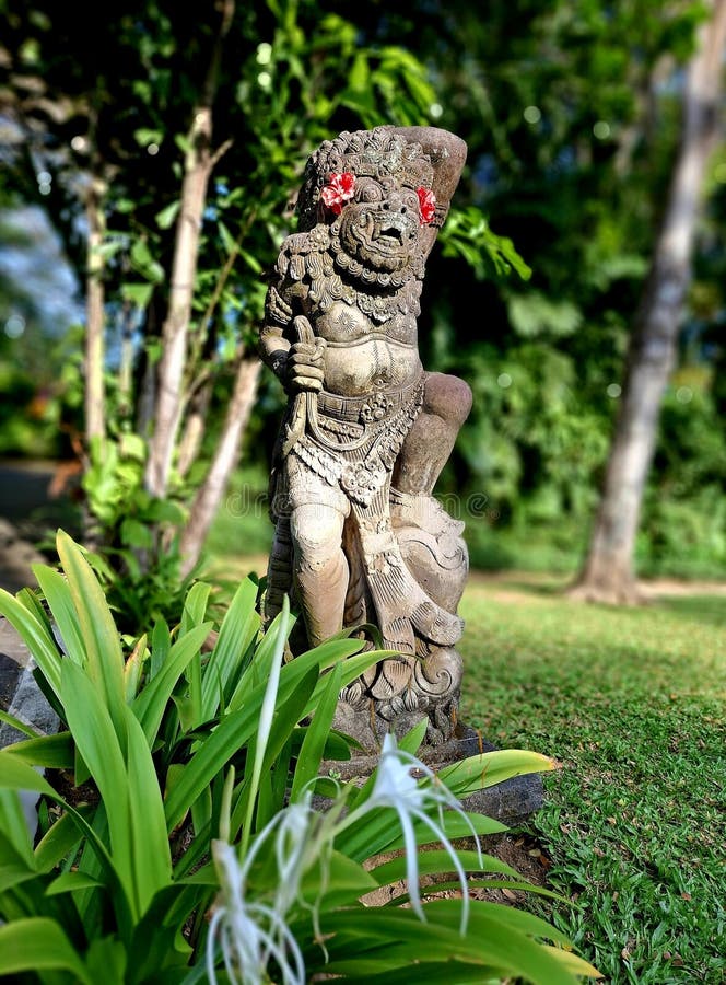 Traditional Balinese statue wearing red flowers royalty free stock image