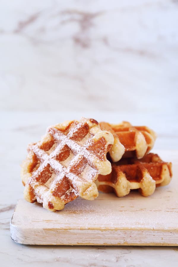 Waffles with Powdered Sugar Serving in a High Slide on a White Plate on a Table Stock Photo