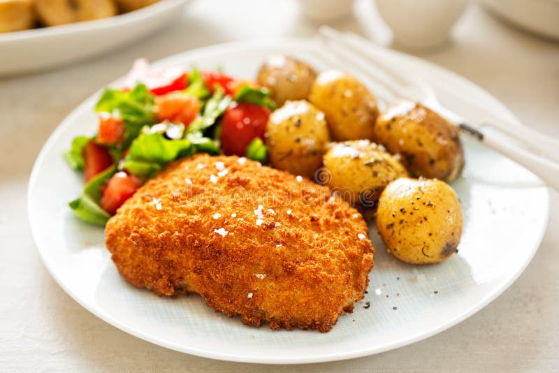 Traditional breaded fillet of cod with baby potatoes and salad royalty free stock photos