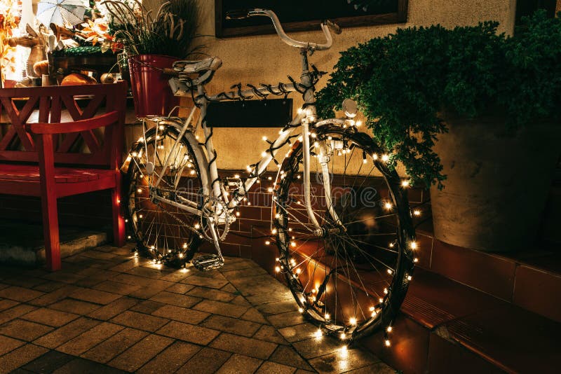 Traditional Christmas decoration on the night street. Vintage bicycle decorated with lights