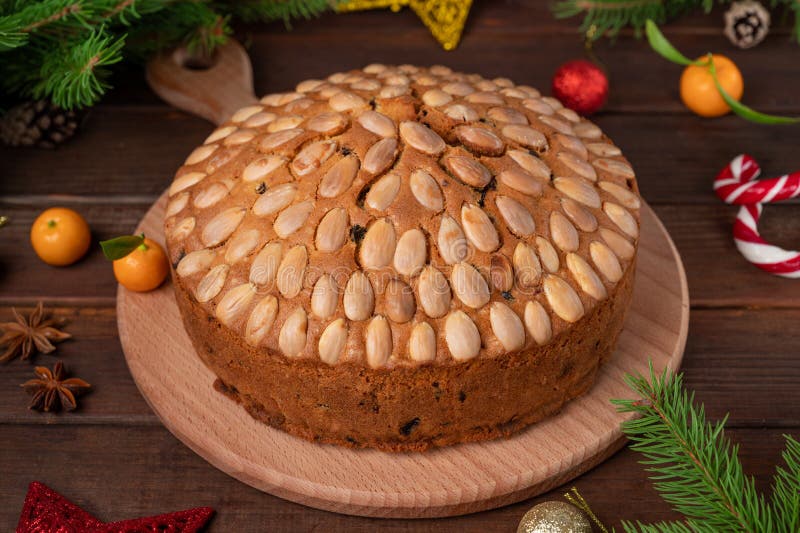 Traditional Christmas Dundee cake with dried fruits and almonds on a wooden board. Festive dessert. Rustic style, selective focus