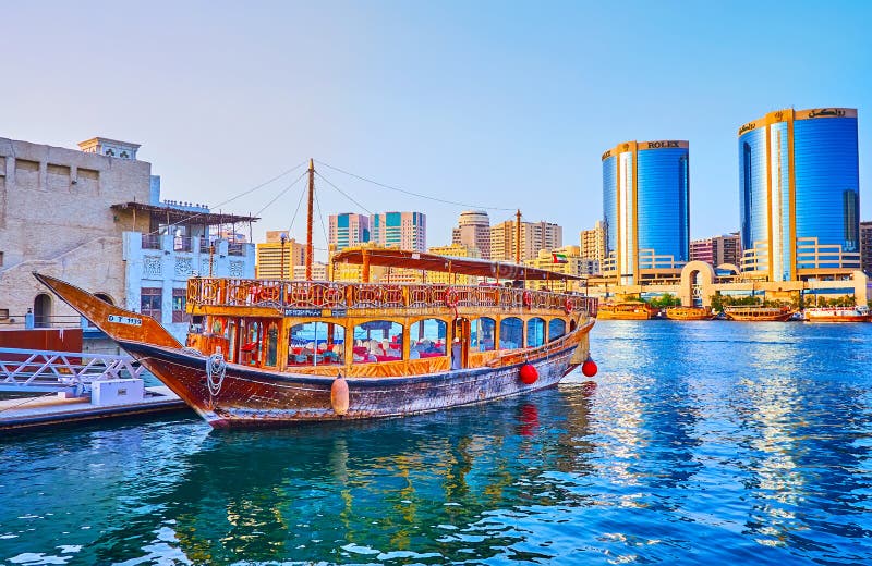 Traditional dhow cruise boat on Dubai Creek against the Deira Twin Towers, on March 1 in Dubai, UAE royalty free stock images