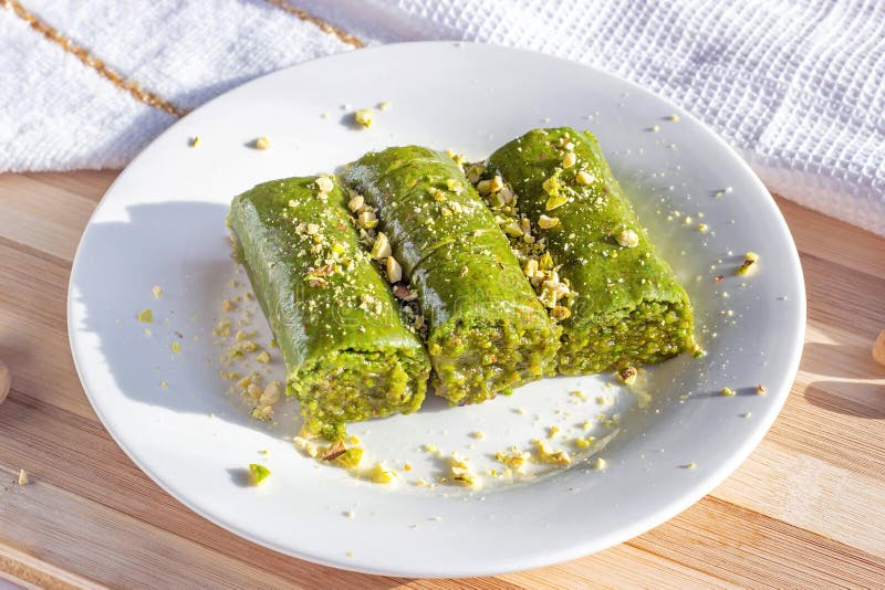 Traditional East Asian sweet baked pistachio bahlava or pahlava with nuts and syrup on a white plate on light wooden background. royalty free stock images Traditional East Asian sweet baked pistachio bahlava or pahlava with nuts and syrup on a white plate on light wooden background. royalty free stock images