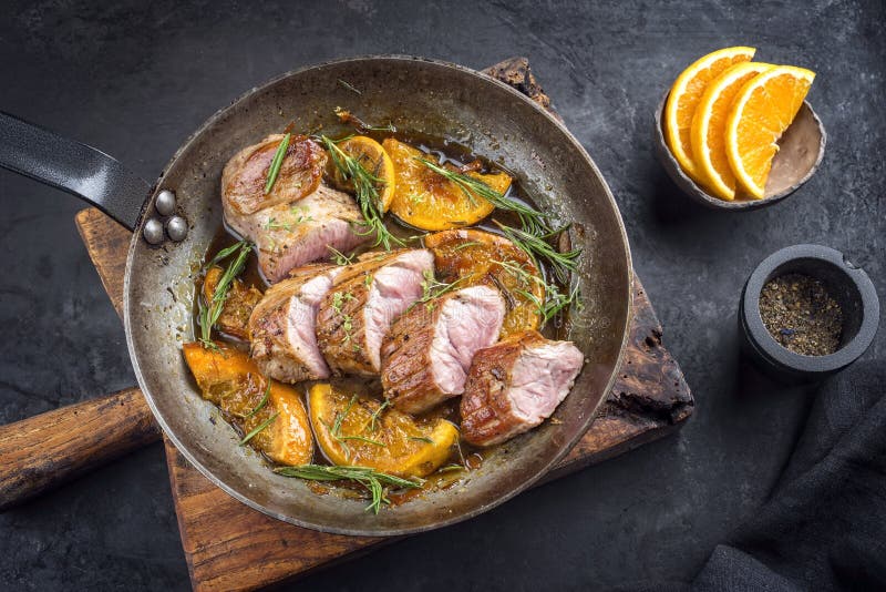 Traditional Fried Pork Filet Medaillons in with Orange Slices and Herbs ...