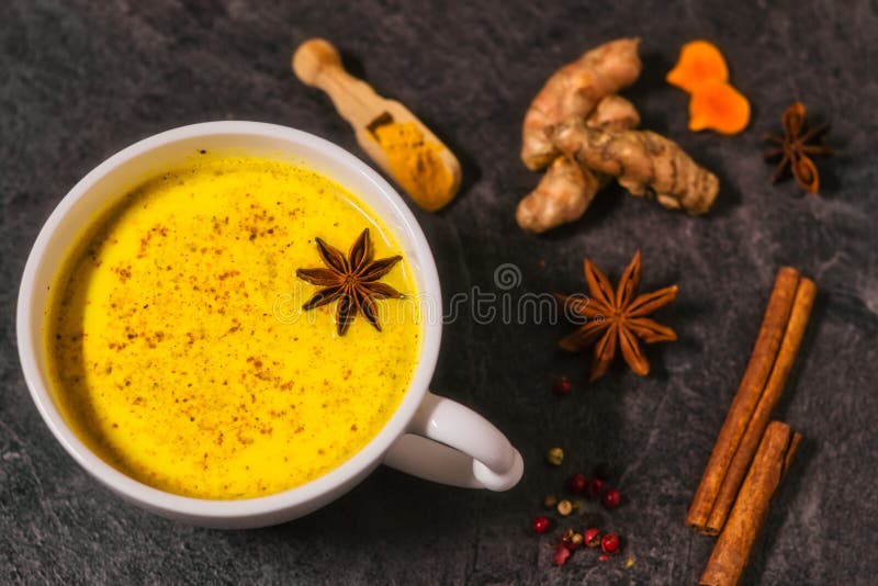Traditional Indian drink, golden milk. With cinnamon, cloves, pepper and turmeric on a wooden background with spices, close up royalty free stock photo Traditional Indian drink, golden milk. With cinnamon, cloves, pepper and turmeric on a wooden background with spices, close up royalty free stock photo