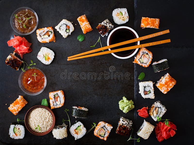 Traditional Japanese food - sushi, rolls and sauce on a dark background.