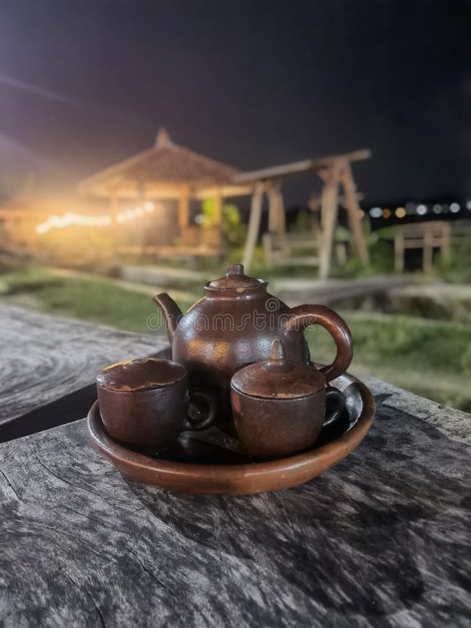 Traditional Javanese Earthenware Tea Set on Rustic Wooden Table at Night royalty free stock photos
