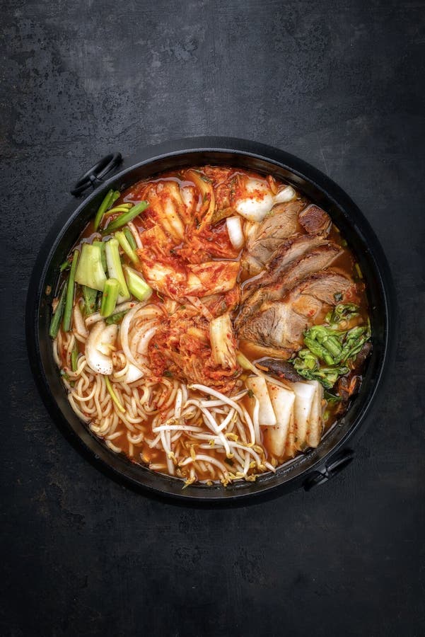 Traditional Korean kimchi jjigae with grilled pork belly and ramen in a design pot