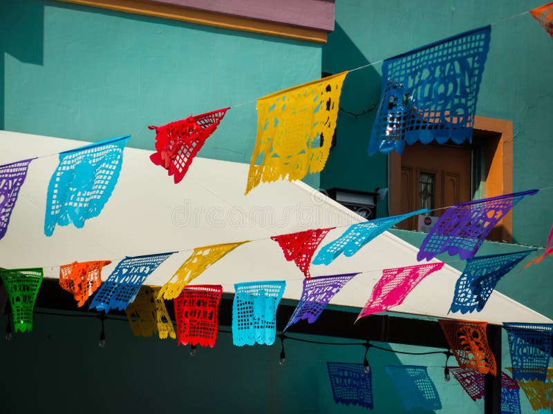 Traditional and colorful mexican banners hanging over San Antonio Mercado for October festival. Turquoise market building in background on sunny summer day. No people. Traditional and colorful mexican banners hanging over San Antonio Mercado for October festival. Turquoise market building in background on sunny summer day. No people