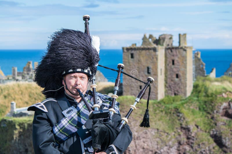 Traditional scottish bagpiper in full dress code at Dunnottar Castle