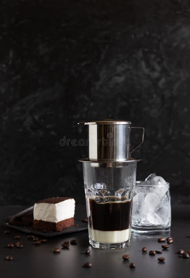 Traditional vietnamese coffee maker placed on the top of glass, glass with ice and souffle dessert