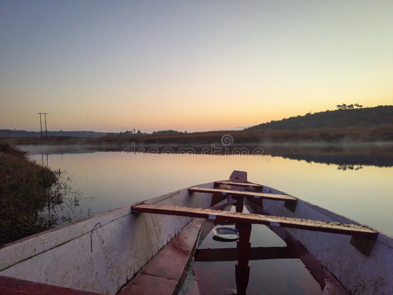 Traditional wood boat at calm lake with dramatic sunrise colorful sky reflection at morning in details