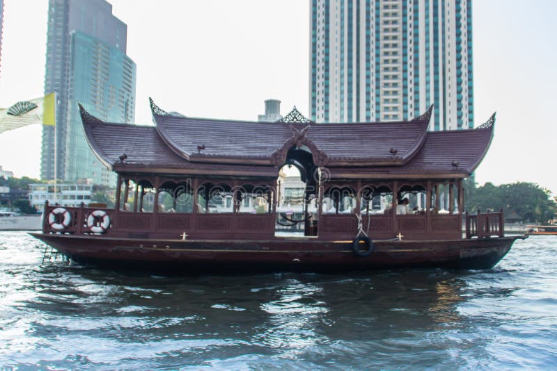 Traditional wooden boat with restaurant on the Chao Phraya river cruising tour. River view of the tourist boat takes visitors for