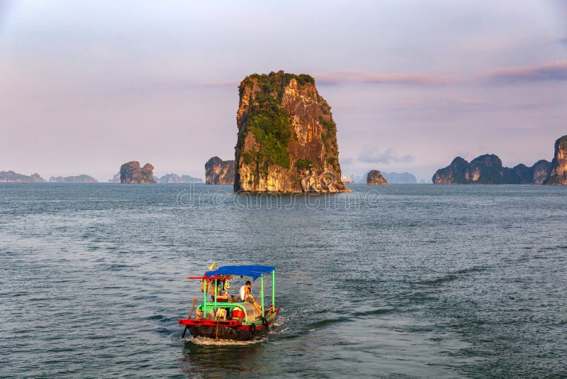 Traditionele vissersboot in Halong-Baai in een purpere zonsondergang, Unesco-wereldnatuurlijk erfgoed, Vietnam stock fotografie Traditionele vissersboot in Halong-Baai in een purpere zonsondergang, Unesco-wereldnatuurlijk erfgoed, Vietnam stock fotografie