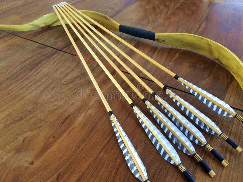 A traditional archery Asiatic recurve bow and six wooden arrows with feather flights. A traditional archery Asiatic recurve bow and six wooden arrows with feather flights.