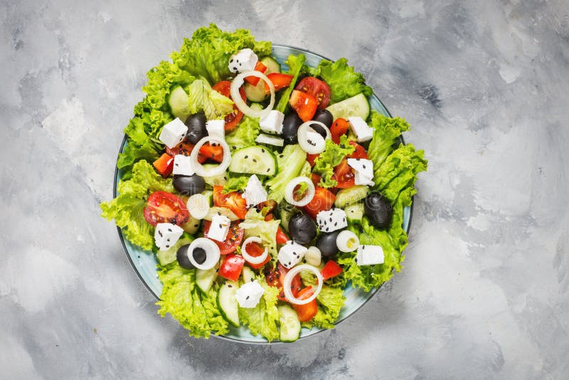 Traditionell grekisk sallad med nya grönsaker, fetaost och oliv på konkret bakgrund Top beskådar arkivfoto Traditionell grekisk sallad med nya grönsaker, fetaost och oliv på konkret bakgrund Top beskådar arkivfoto