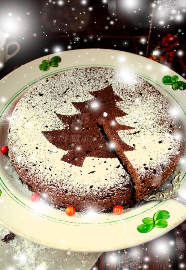 Traditional Homemade chocolate Christmas cake sprinkled with sugar powder, new year tree decoration with snow. Traditional Homemade chocolate Christmas cake sprinkled with sugar powder, new year tree decoration with snow