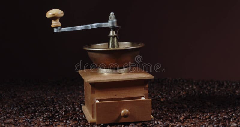 Traditionell manuell kaffekvarn. trä och koppar. kaffebönor kanelkryddor i mörk bakgrund. kamera