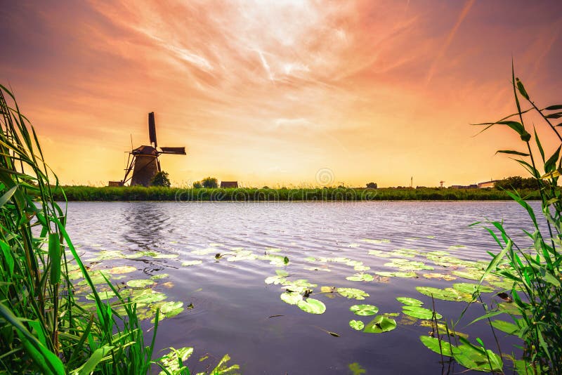 Traditionell by med holländska väderkvarnar och floden på solnedgången, Holland, Nederländerna arkivbilder Traditionell by med holländska väderkvarnar och floden på solnedgången, Holland, Nederländerna arkivbilder