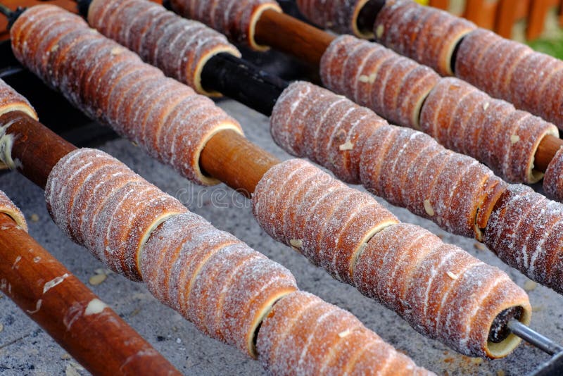 Traditionelles tschechisches Lebensmittel ` Trdelnik-` Ein populärer Teller unter Touristen zu auf hölzerne Aufsteckspindeln über stockbild Traditionelles tschechisches Lebensmittel ` Trdelnik-` Ein populärer Teller unter Touristen zu auf hölzerne Aufsteckspindeln über stockbild