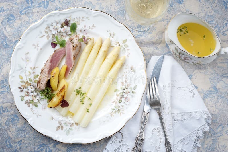 Traditionellt skivat fläskfiléstäcke med vit sparris i smörsås och rostat potatis på en klassisk skylt. royaltyfri foto