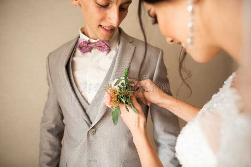 Tradycjonalnie panna młoda w domu dotyka małego bukiet dla fornala Fornala bukiet obok ręki na kostiumu obraz stock Tradycjonalnie panna młoda w domu dotyka małego bukiet dla fornala Fornala bukiet obok ręki na kostiumu obraz stock