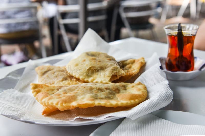 Tradycyjny smażący ciasto dzwoniący «çi börek «zrobił z surowym zmielonym mięsem, cebulami i pikantność słuzyć z Turecką herbatą, zdjęcie stock Tradycyjny smażący ciasto dzwoniący «çi börek «zrobił z surowym zmielonym mięsem, cebulami i pikantność słuzyć z Turecką herbatą, zdjęcie stock