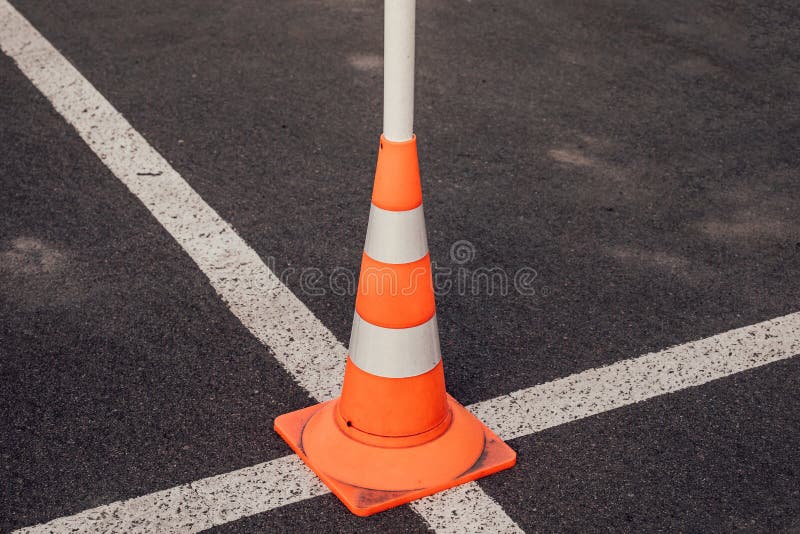 Traffic cone at the intersection of the white lines of road markings. Symbol of restrictions, road works, attention. For