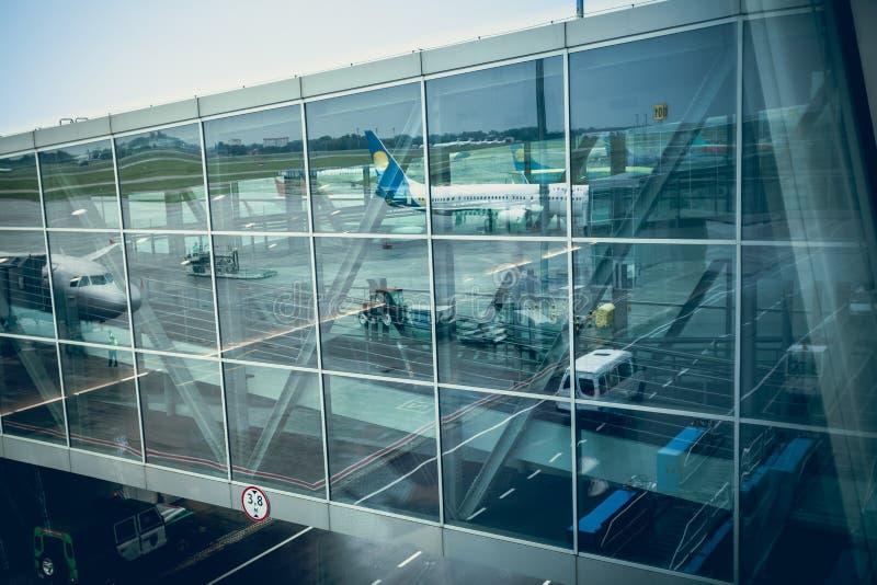 Trafikflygplan som reflekterar i glasvägg av den moderna flygplatsterminalen arkivbilder Trafikflygplan som reflekterar i glasvägg av den moderna flygplatsterminalen arkivbilder