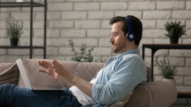 Tragen Kopfhörer des Seitenansichtmannes mithilfe des Notebooks, der Videokonferenz macht stockbild