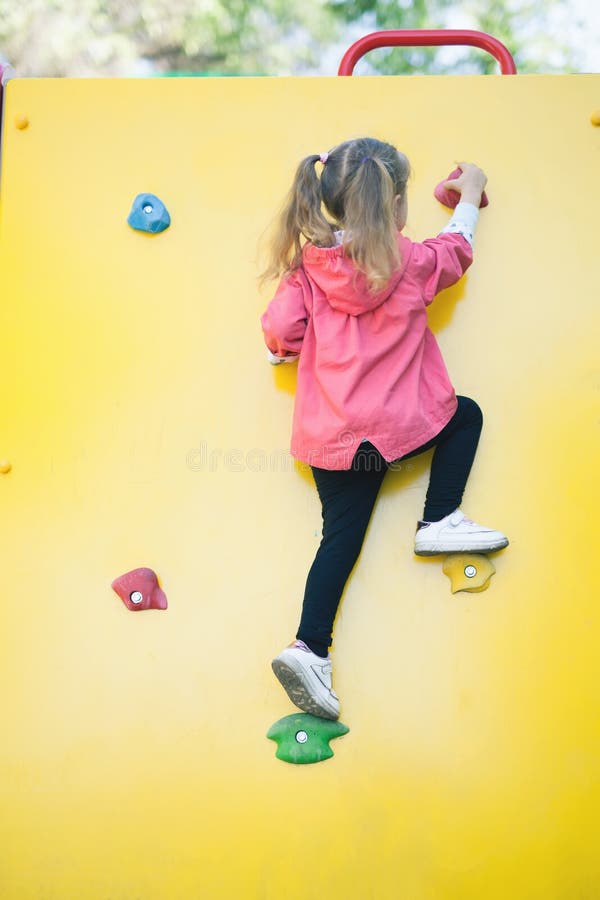 Tragen Sie Bild des Kletterns des kleinen Mädchens zur Spitze der Wand zur Schau lizenzfreie stockbilder Tragen Sie Bild des Kletterns des kleinen Mädchens zur Spitze der Wand zur Schau lizenzfreie stockbilder
