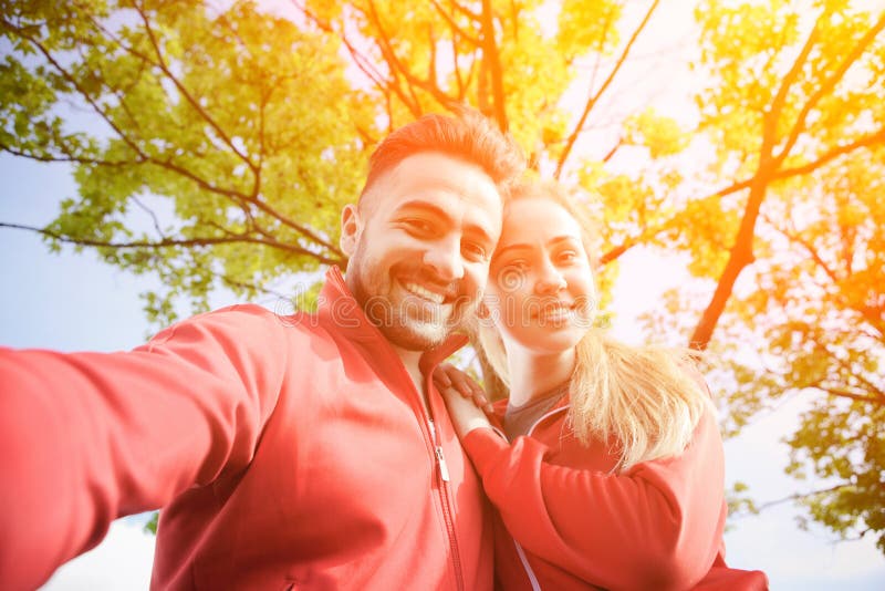Tragen Sie den Mann und Frau zur Schau, die selfies im Park machen