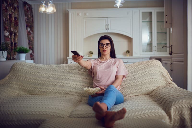 Tragende Gläser eines Brunettemädchens mit dem Popcorn, das in fernsieht stockbild Tragende Gläser eines Brunettemädchens mit dem Popcorn, das in fernsieht stockbild