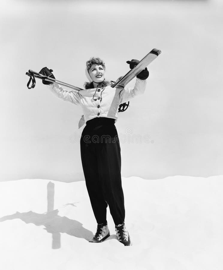 Tragender Ski der jungen Frau und Skipfosten auf ihren Schultern (alle dargestellten Personen sind nicht längeres lebendes und ke