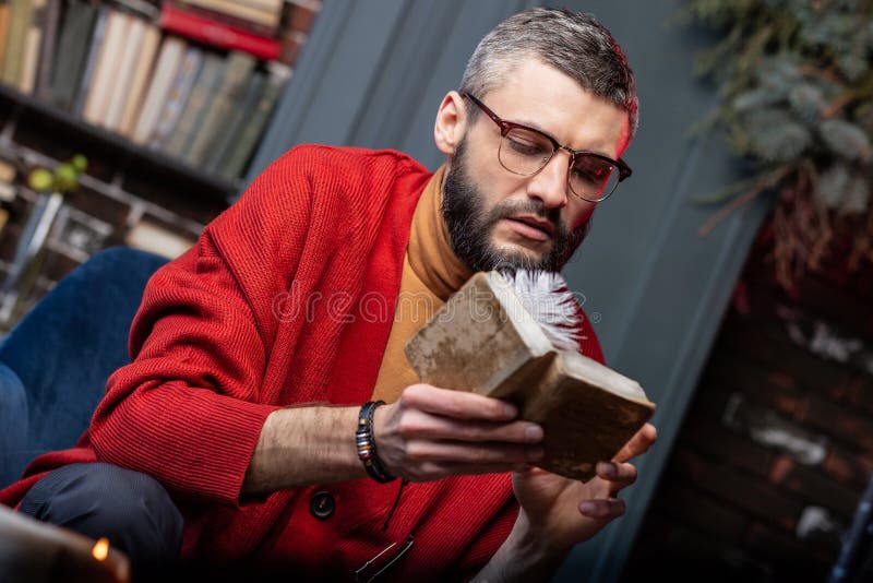 Tragendes Armband des bärtigen reifen Wahrsagers, das wenig altes Magierbuch hält stockbild Tragendes Armband des bärtigen reifen Wahrsagers, das wenig altes Magierbuch hält stockbild