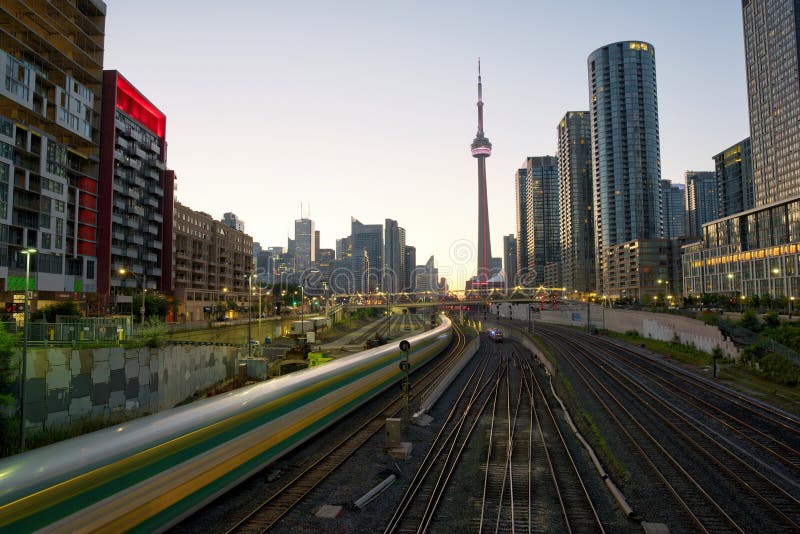 Train in downtown of Toronto with highrise buildings and CN Tower at sunrise