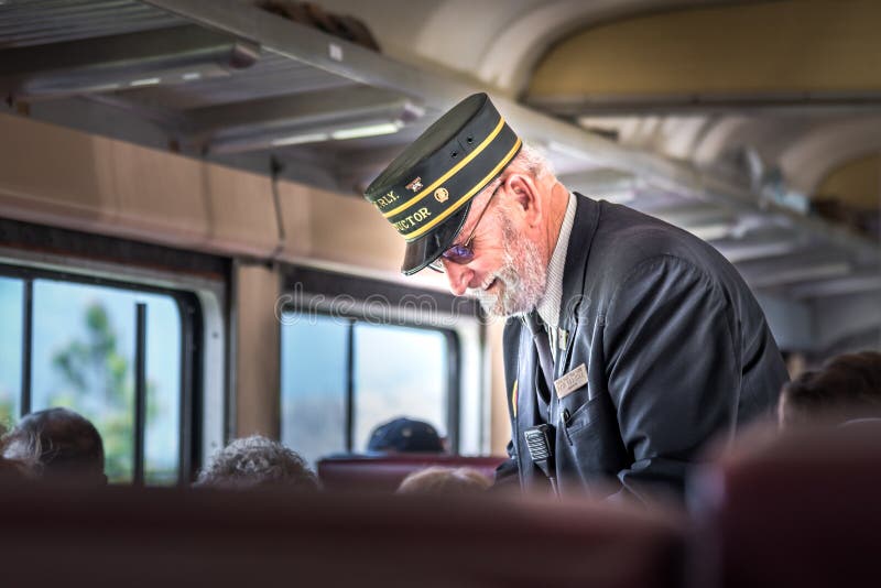 Train conductor taking tickets from passengers.