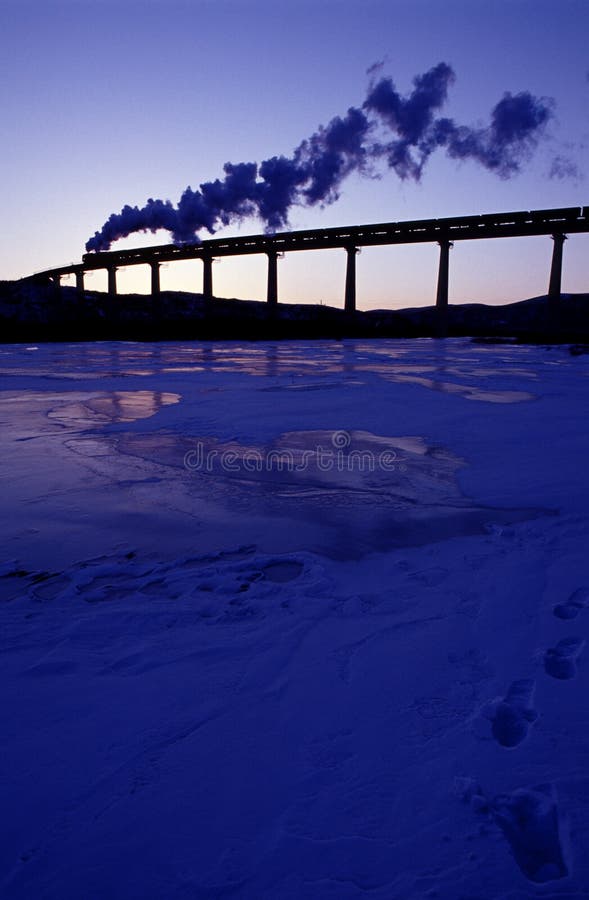 Steam train runs across a bridge over a glacier river. Steam train runs across a bridge over a glacier river