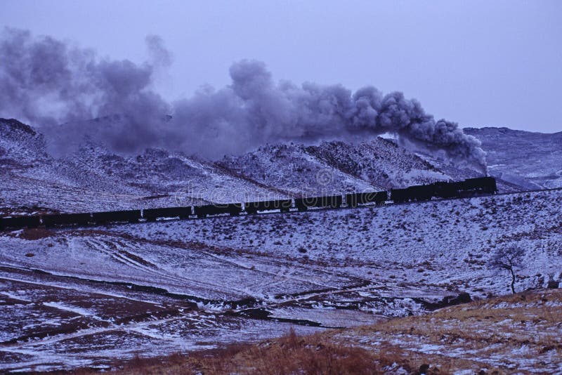 Steam train runs across the snowy mountain. Steam train runs across the snowy mountain