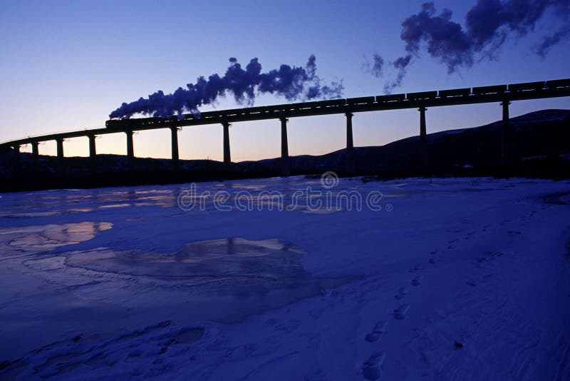 Steam train runs across a bridge over a glacier river. Steam train runs across a bridge over a glacier river