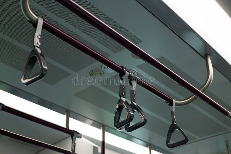 Train handrails and straps in modern transportation system. The image emphasizes metal and fabric design of the hand grips stock photo