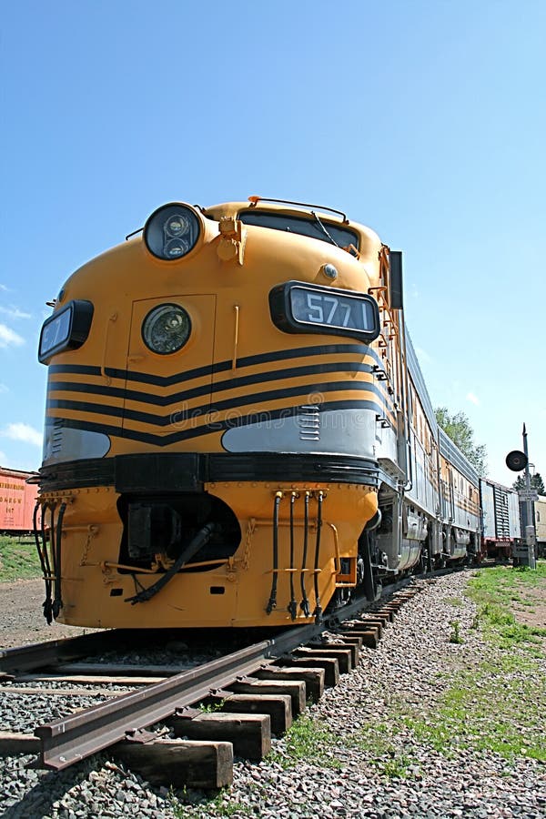 A beautiful long yellow train stretches down the tracks for a long ways. A beautiful long yellow train stretches down the tracks for a long ways.