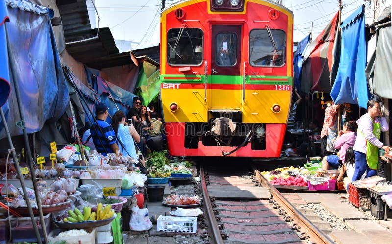 Train passing through Maeklong railway market, Thailand