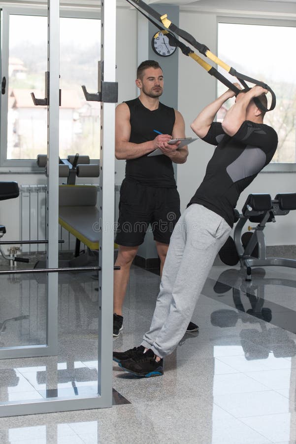 Trainer With Clipboard Man On Trx Fitness Straps stock image Trainer With Clipboard Man On Trx Fitness Straps stock image