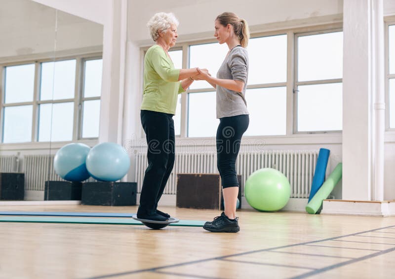 Trainer helping senior woman exercising with a bosu balance stock images Trainer helping senior woman exercising with a bosu balance stock images