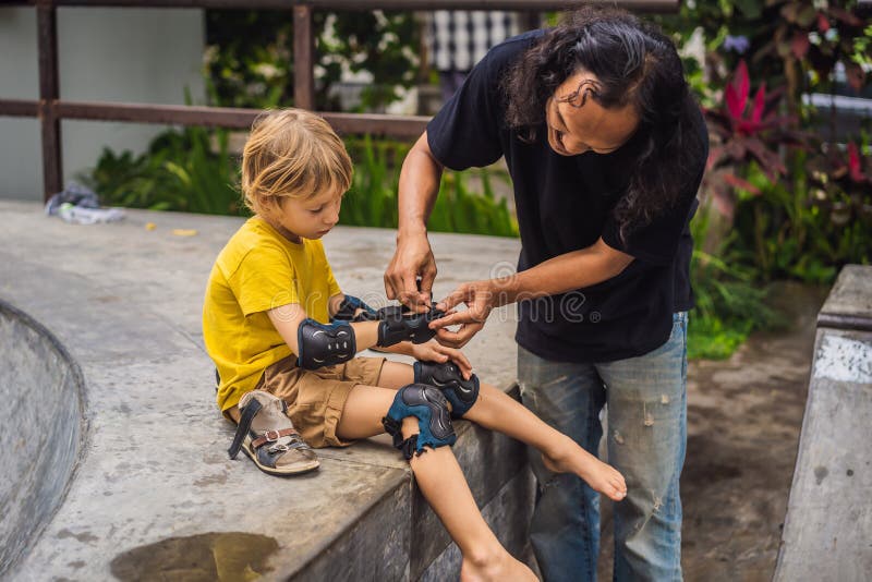 Trainer helps the boy to wear knee pads and armbands before training skate board royalty free stock photo Trainer helps the boy to wear knee pads and armbands before training skate board royalty free stock photo